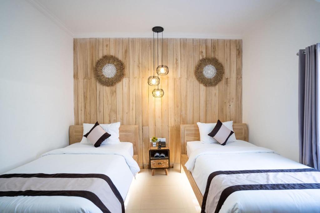 two beds in a room with wooden walls at Oki Taru Residence in Kuta