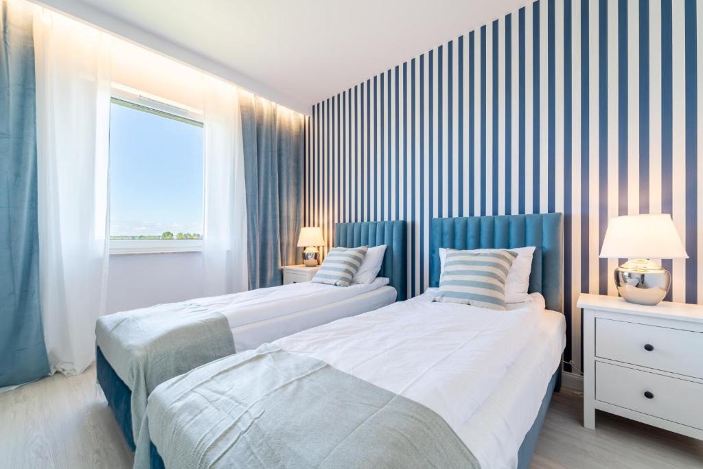 two beds in a bedroom with a striped wall at Bella Vista Apartment in Iława