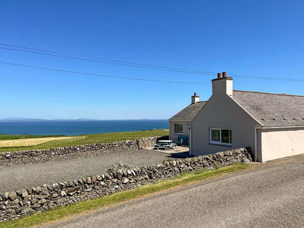 a house with a stone wall next to a road at Auld Dairy Cottage in Drummore