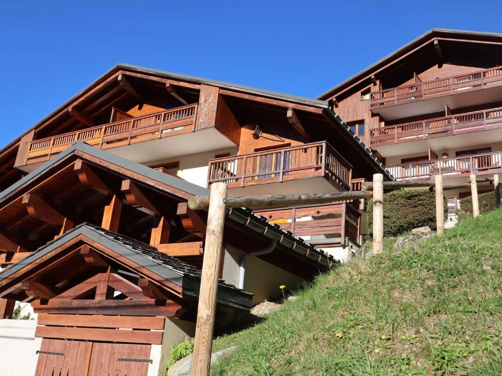 un bâtiment avec des balcons en bois au sommet d'une colline dans l'établissement Appartement lumineux 2 chambres, parking, terrasse, proche commerces et pistes à Arêches-Beaufort - FR-1-342-226, à Beaufort