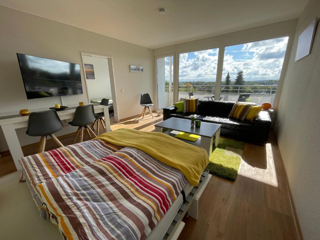 ein Schlafzimmer mit einem Bett und einem Sofa und einem großen Fenster in der Unterkunft Haus Weitblick Lia in Flensburg