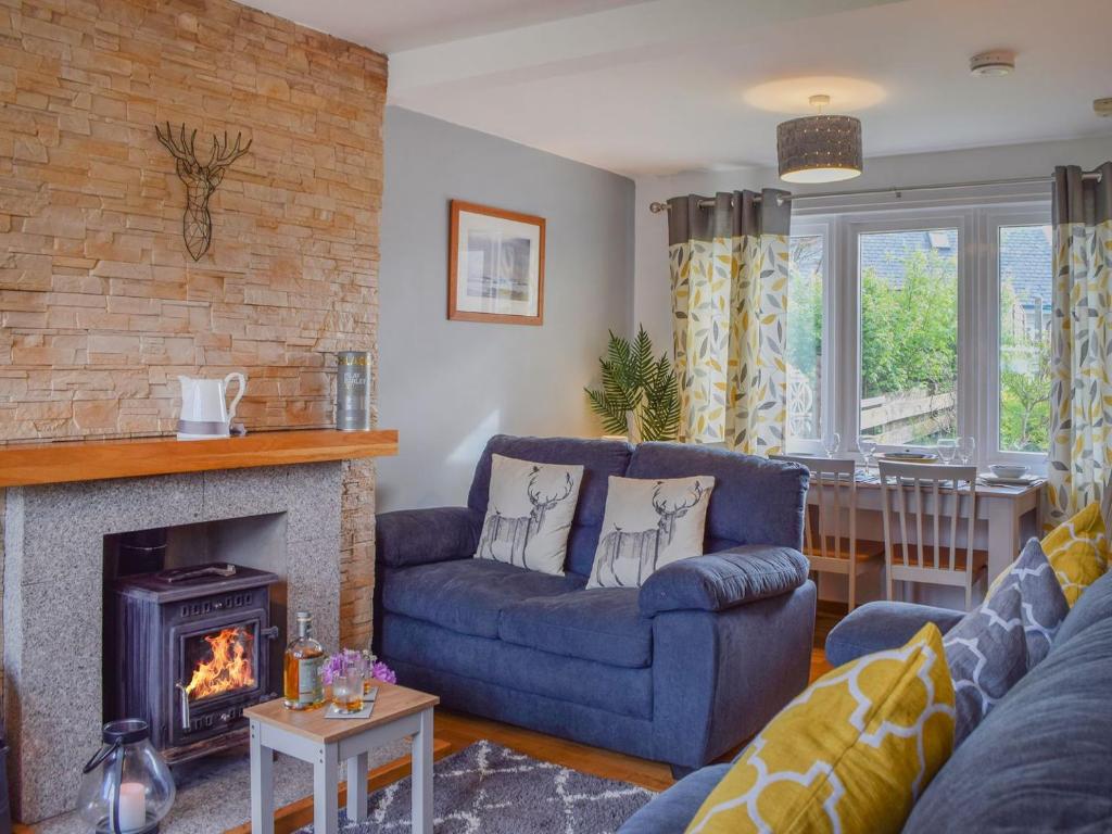 a living room with a blue couch and a fireplace at Burnside Cottage in Bruichladdich