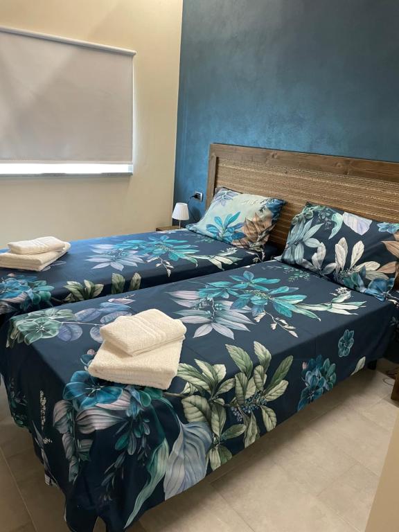 1 dormitorio con 2 camas con colchas azules y verdes en B&B La DORMERIA, en Finale Ligure