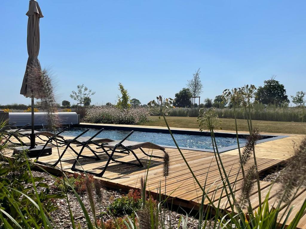 une terrasse en bois avec une piscine dans un jardin dans l'établissement Aurefees, à Ellon