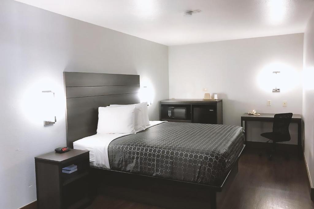 a bedroom with a bed and two tables and a chair at Sky Palace Inn By Jasper Near AT & T Center in San Antonio