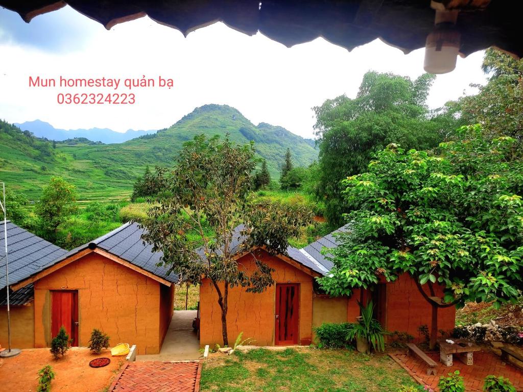 a small house with mountains in the background at Mun Homestay in Ha Giang