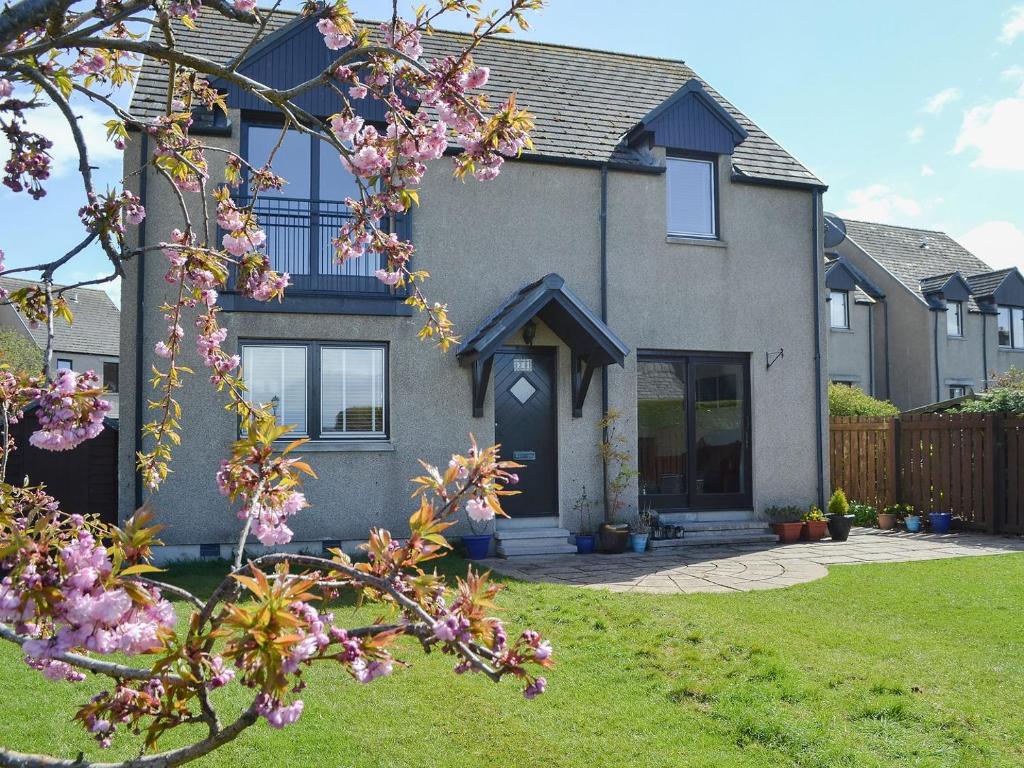 a house with a flowering tree in front of it at Beach View in Nairn