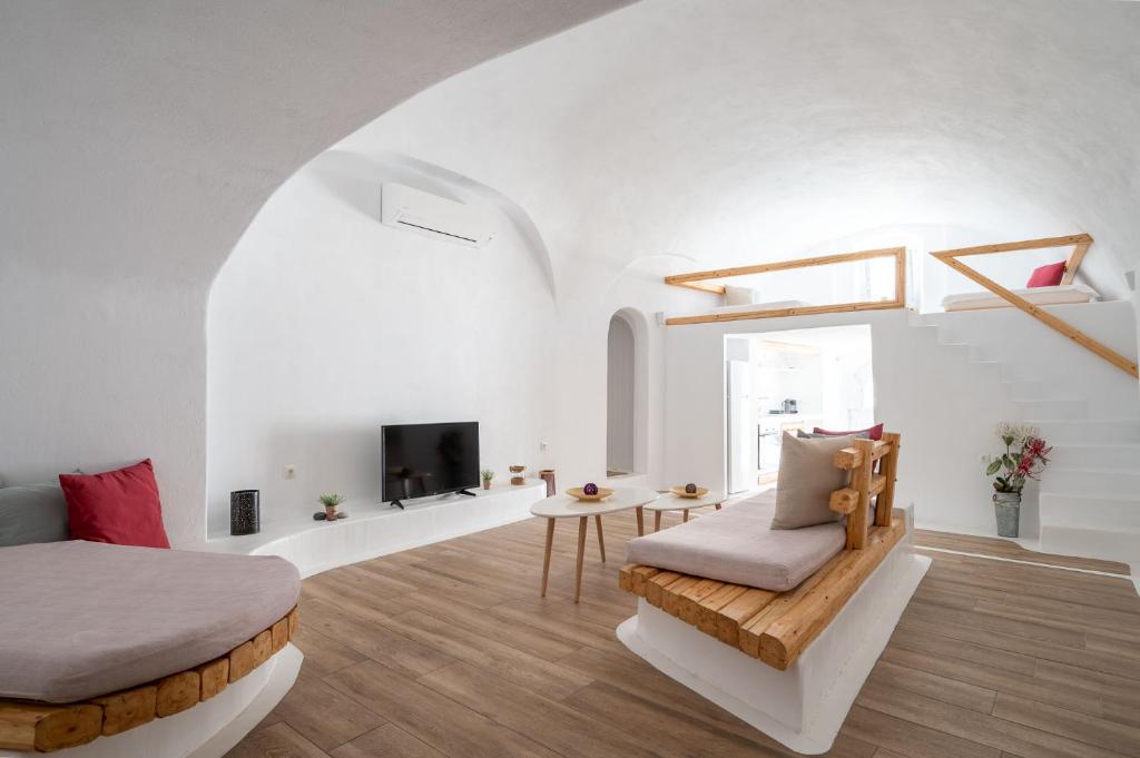 una stanza bianca con un letto e una tv di Karpimo Suites a Éxo Goniá