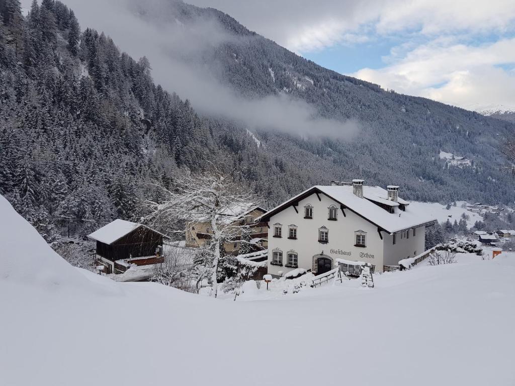 a house in the snow in front of a mountain at Apartments HAUS SCHÖN - Preise inclusive Pitztal Sommer Card in Jerzens