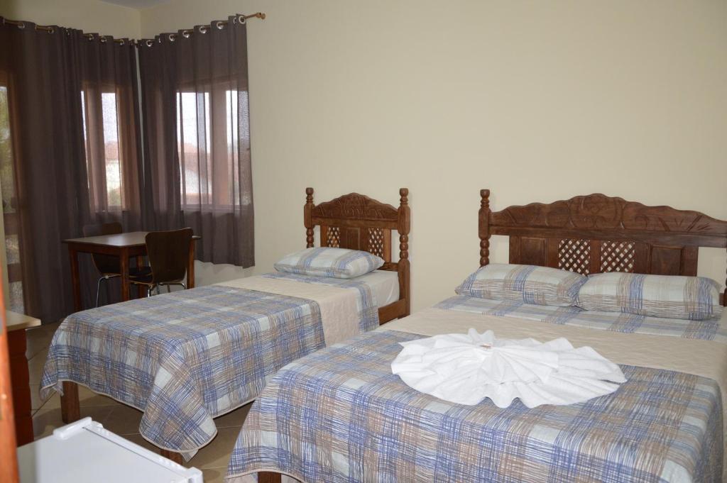 a hotel room with two beds and a table at Hotel Colonial in Pôrto Real