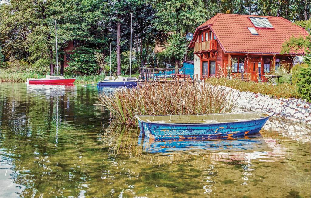 a boat sitting in the water next to a house at Stunning Home In Stawiguda With Kitchenette in Stawiguda