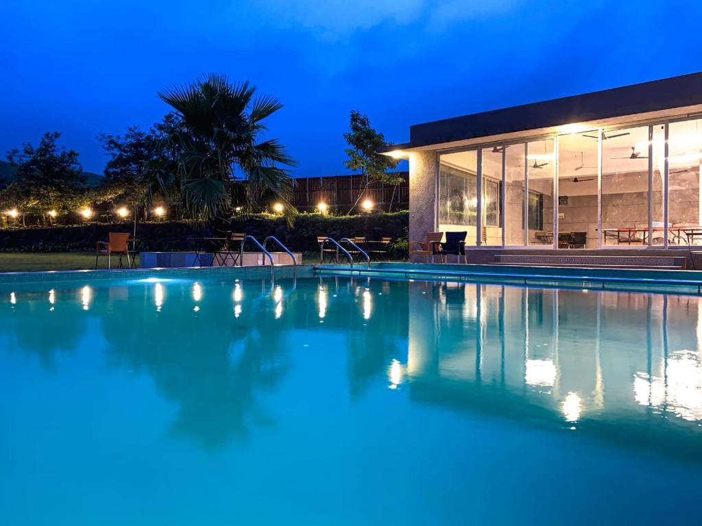een zwembad voor een huis 's nachts bij Le Jardin Resort and Spa in Karjat