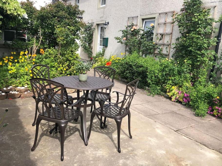 a black table and chairs with a table and flowers at Kings Cottage, Nairn - a charming place to stay in Nairn