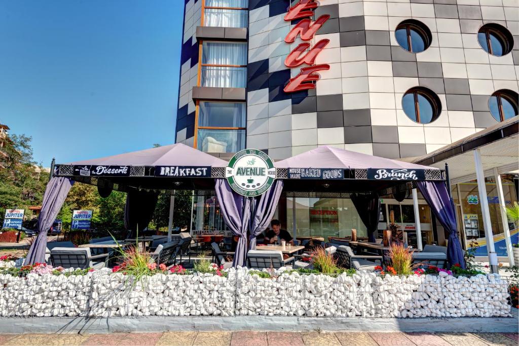 a restaurant with tables and chairs in front of a building at Hotel Avenue in Sunny Beach