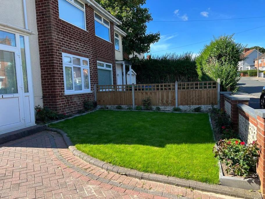 a lawn in front of a house with a fence at Gated home close to Birmingham City Centre in Birmingham