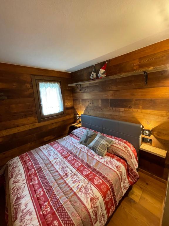 a bedroom with a bed with wooden walls and a window at Baita del Cervino CIR n 0016 in Breuil-Cervinia