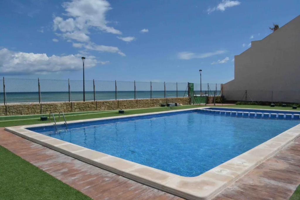 uma piscina com a praia ao fundo em Modern beachfront townhouse em El Perelló