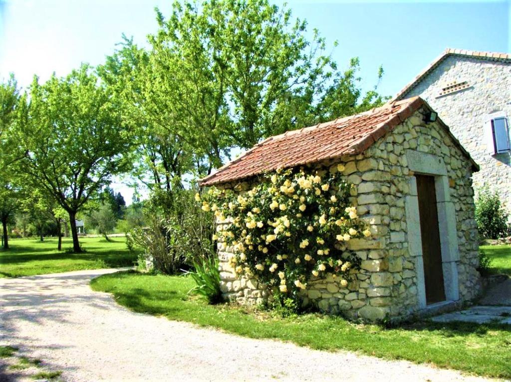 a stone building with a bush of flowers on it at CHAMBRES D&#39;HOTES 2 à 4p ou GITE DE GROUPE 15p, 7 ch, 6 sdb, parc et salle de réception in Villeneuve-de-Berg