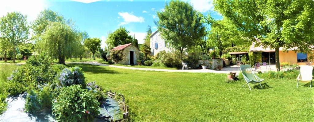 a yard with a green chair and a house at CHAMBRES D&#39;HOTES 2 à 4p ou GITE DE GROUPE 15p, 7 ch, 6 sdb, parc et salle de réception in Villeneuve-de-Berg