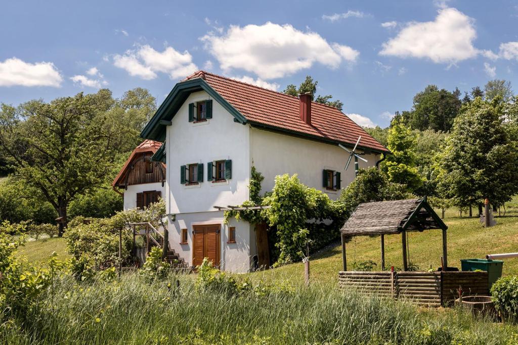 biały dom z czerwonym dachem na polu w obiekcie Kellerstöckl Postrumer Weinberg 49 w mieście Kulm im Burgenland