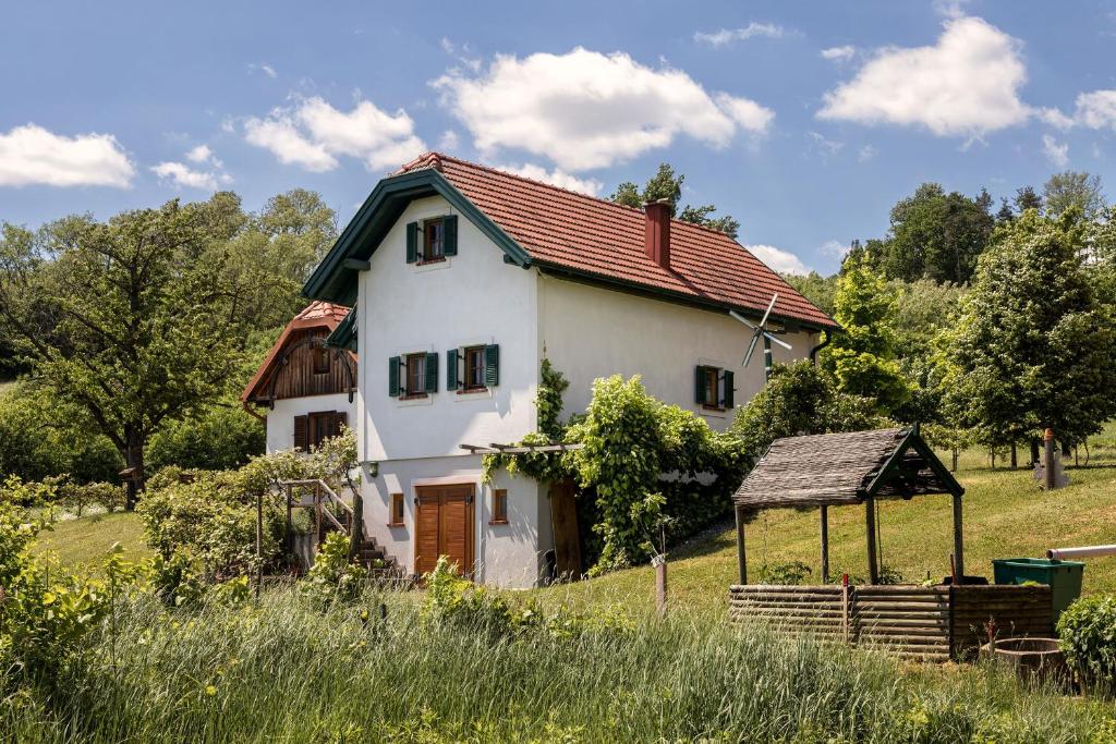 ein weißes Haus mit rotem Dach auf einem Feld in der Unterkunft Kellerstöckl Postrumer Weinberg 49 in Kulm im Burgenland