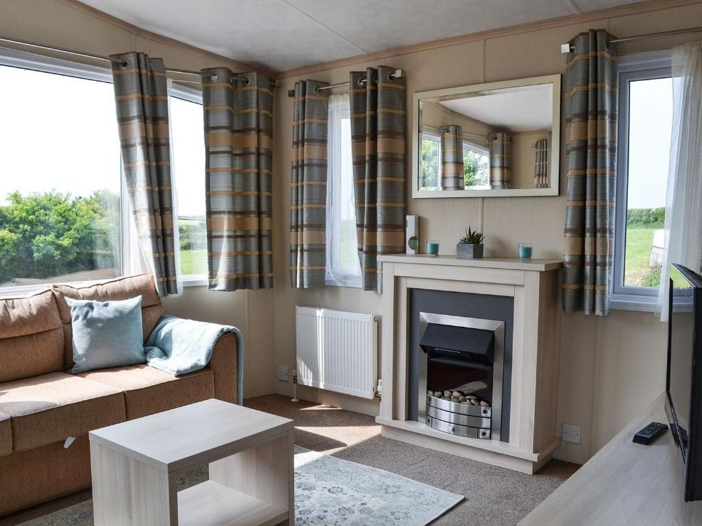 een woonkamer met een bank en een open haard bij Neuadd Wen Cottages - Porthdy Crey R Wen in Llanfachraeth
