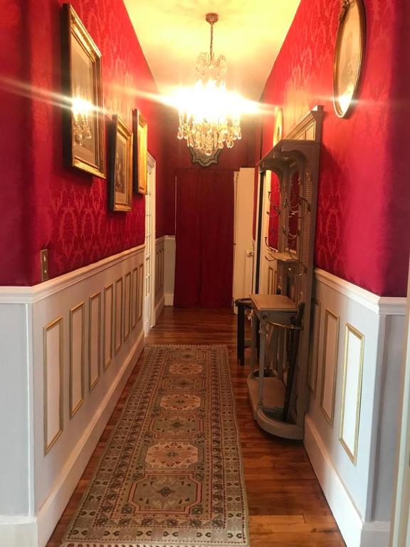 a hallway with red walls and a chandelier at VICHY LUXE NAPOLEON III in Vichy