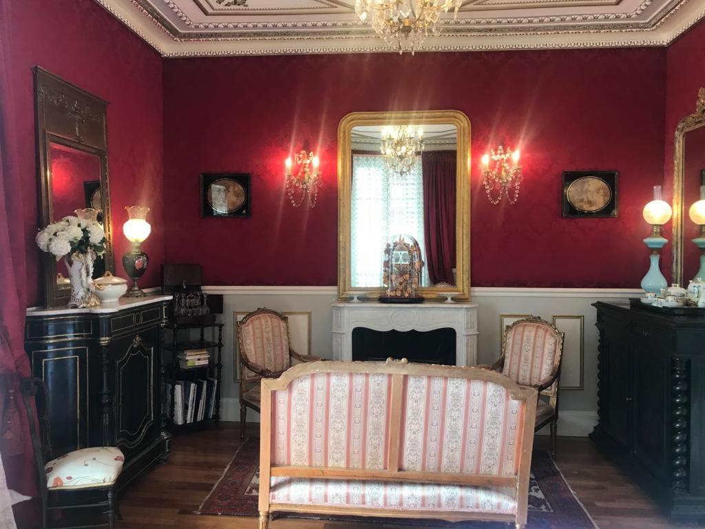 a living room with red walls and a mirror at VICHY LUXE NAPOLEON III in Vichy