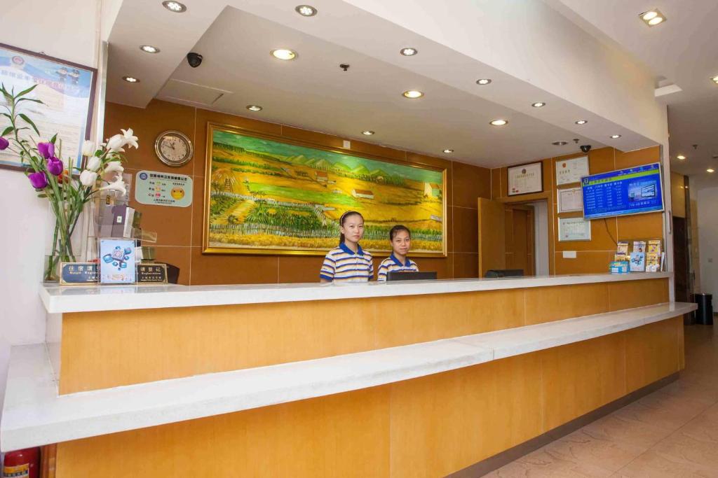 two people standing at a counter in a restaurant at 7Days Inn Tai'an Railway Station in Tai'an