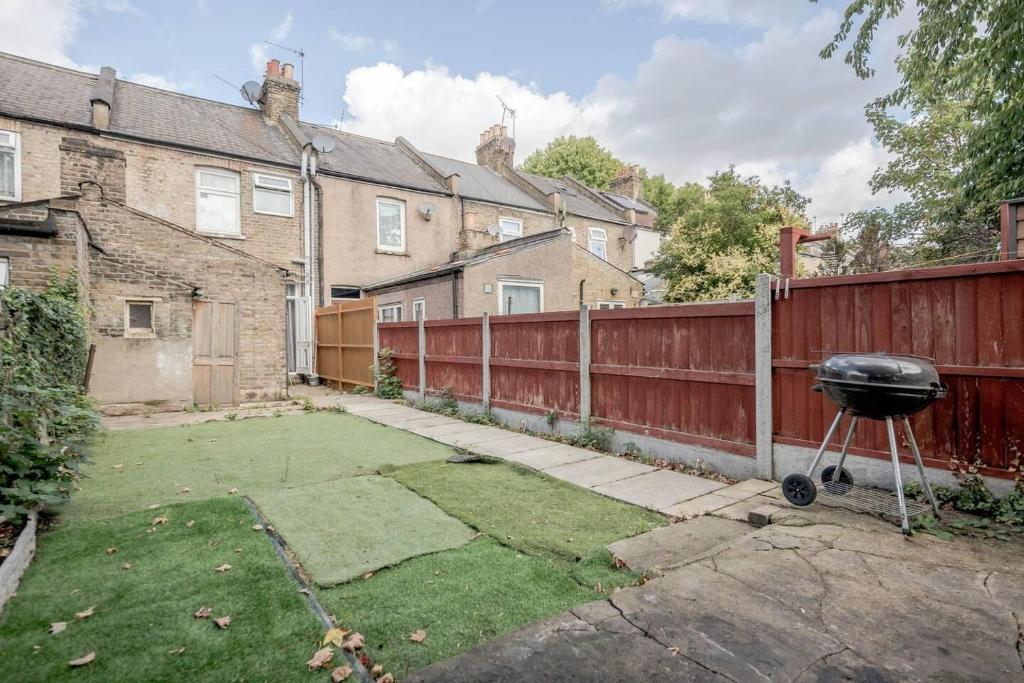 a barbecue grill in a yard next to a fence at Impeccable and welcoming 3-Bed House in London in London