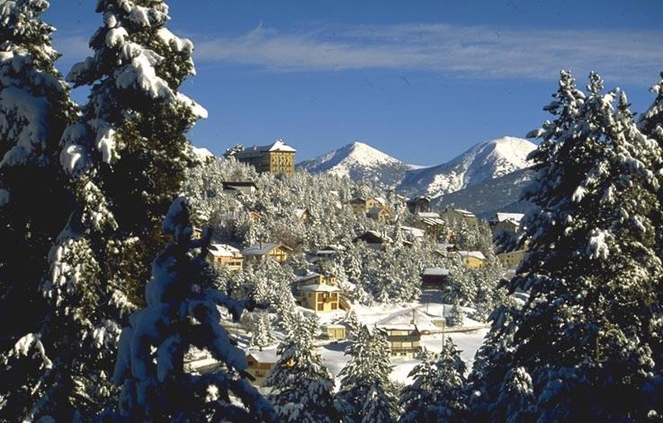 un village recouvert de neige avec des montagnes en arrière-plan dans l'établissement Font-Romeu village - ski, randonnées, loisirs plein air, à Font-Romeu-Odeillo-Via