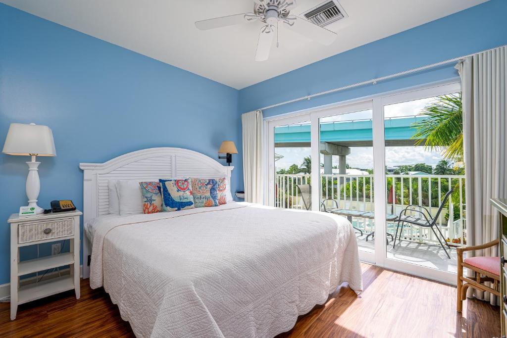 a bedroom with a white bed and a balcony at Harbour House at the Inn 313 in Fort Myers Beach