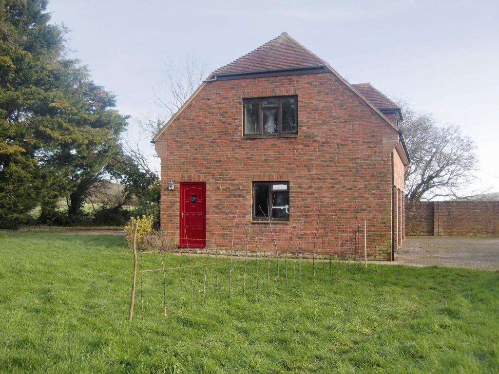 een oud stenen huis met een rode deur in een veld bij Greenwood Cottage in Sandown