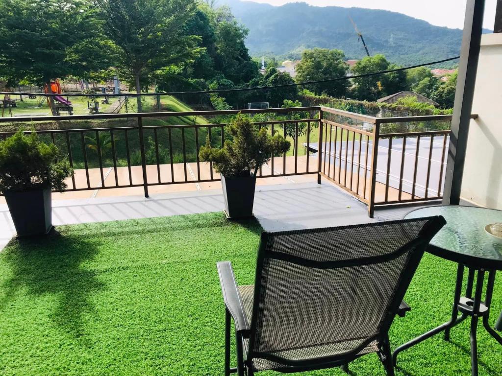 einen Balkon mit einem Tisch und einem Stuhl auf dem Rasen in der Unterkunft Mountain View Homestay in Seremban