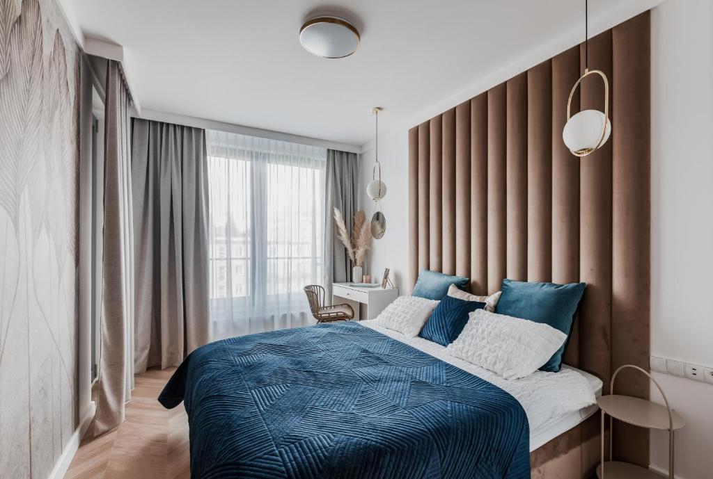 a bedroom with a large bed with a blue blanket at Prime Plac Unii in Gdynia