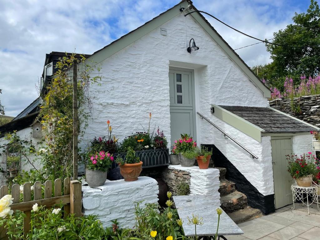 a white cottage with potted plants on the stairs at The Hayloft, Exmoor in Withypool