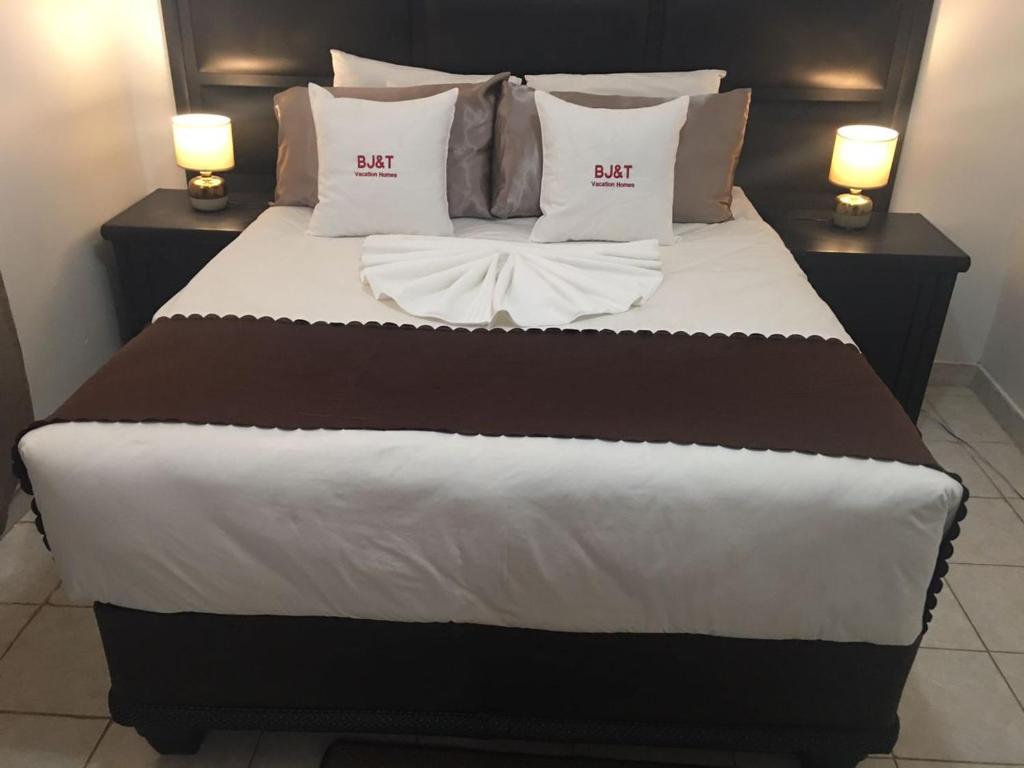 Cette chambre comprend un grand lit avec des draps et des oreillers blancs. dans l'établissement BJ&T Vacation Homes, à Kasane