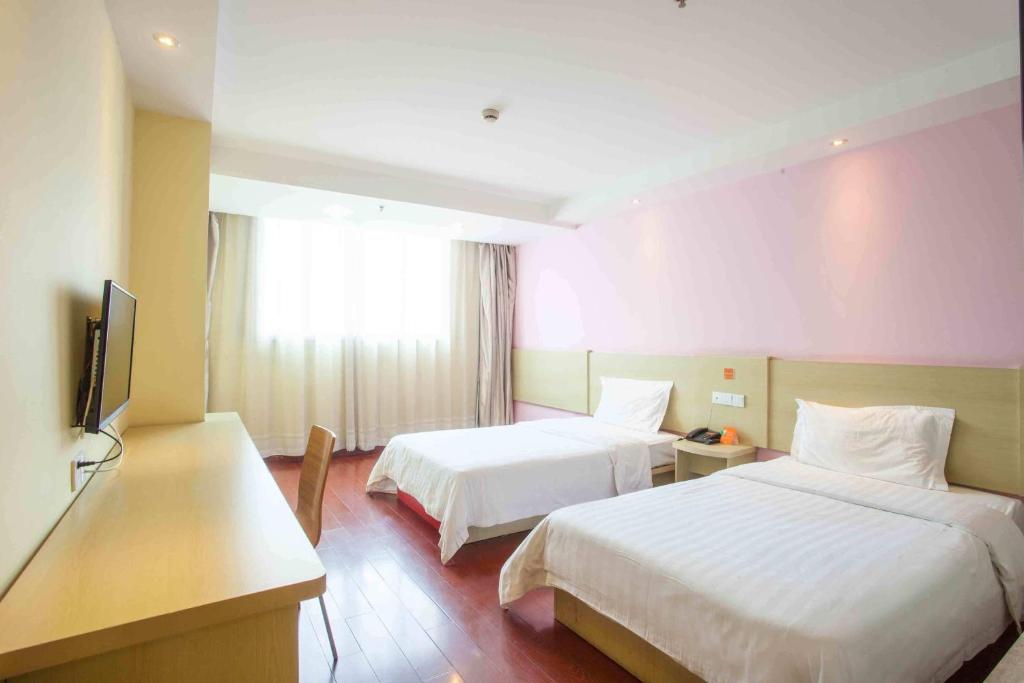 a hotel room with two beds and a television at 7Days Inn Laiwu Fengcheng West Street in Laiwu