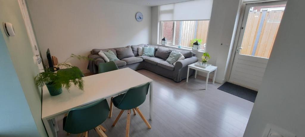 ein Wohnzimmer mit einem Sofa, einem Tisch und Stühlen in der Unterkunft Duinhuis26 in Egmond aan Zee
