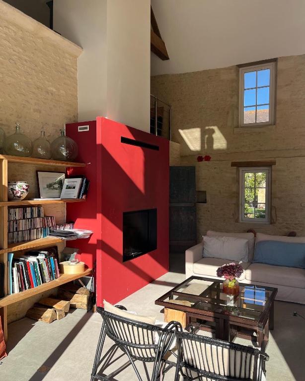 a living room with a red wall and a couch at Les Granges Pelloquin in Bernières-sur-Mer