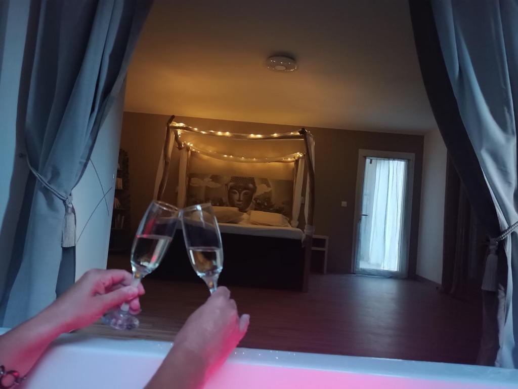 two people holding wine glasses in front of a bedroom at séjour bien-être balnéothérapie en vallée heureuse à Sorede in Sorède