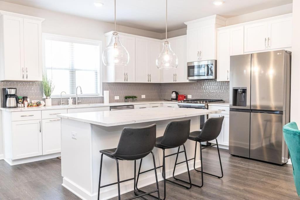 a kitchen with white cabinets and a large island with chairs at New spacious 3 bedroom suite garage parking free Wi-Fi office space and patio view in Duluth