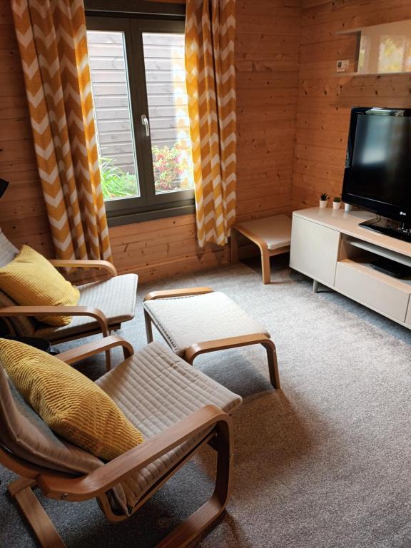 a living room with a flat screen tv and chairs at Nancy's Cabin in Mosborough