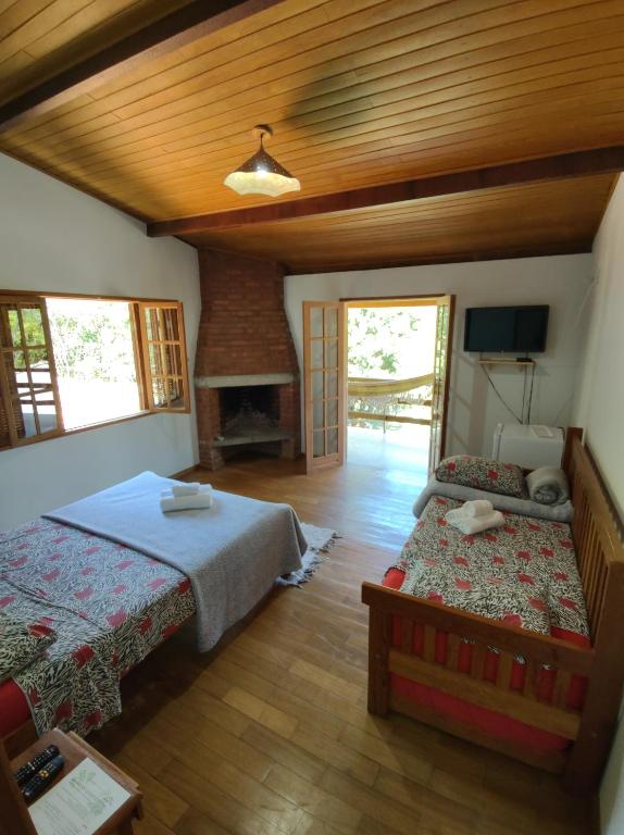 een slaapkamer met 2 bedden en een open haard bij Pousada Sangha Pyara in Conceição da Ibitipoca