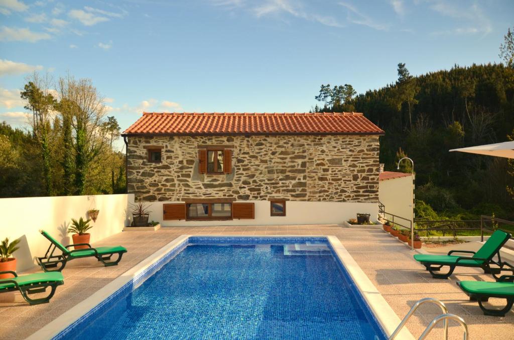 a villa with a swimming pool in front of a house at Casa Lerryn in Sertã