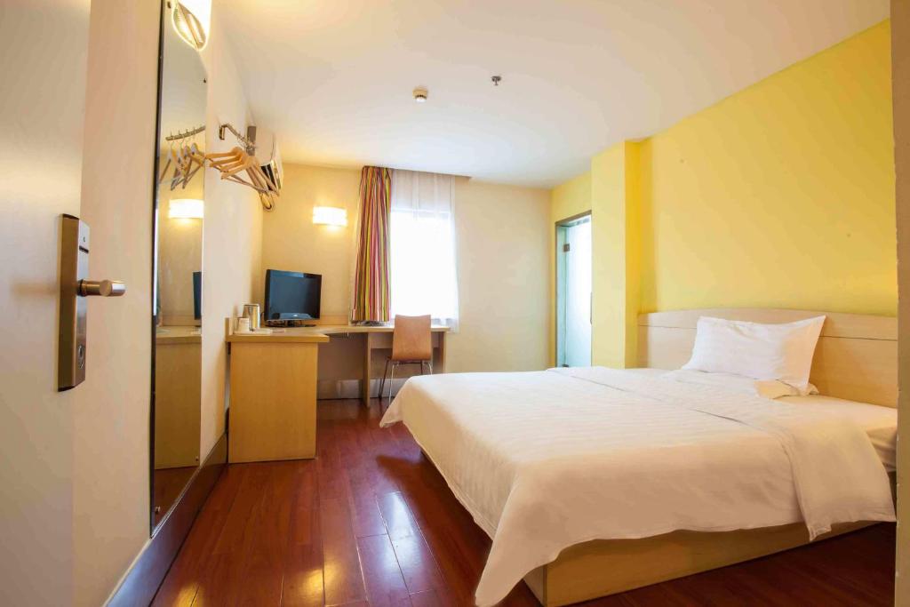 a bedroom with a bed and a desk with a television at 7Days Inn Shaoguan Book Shop in Shaoguan