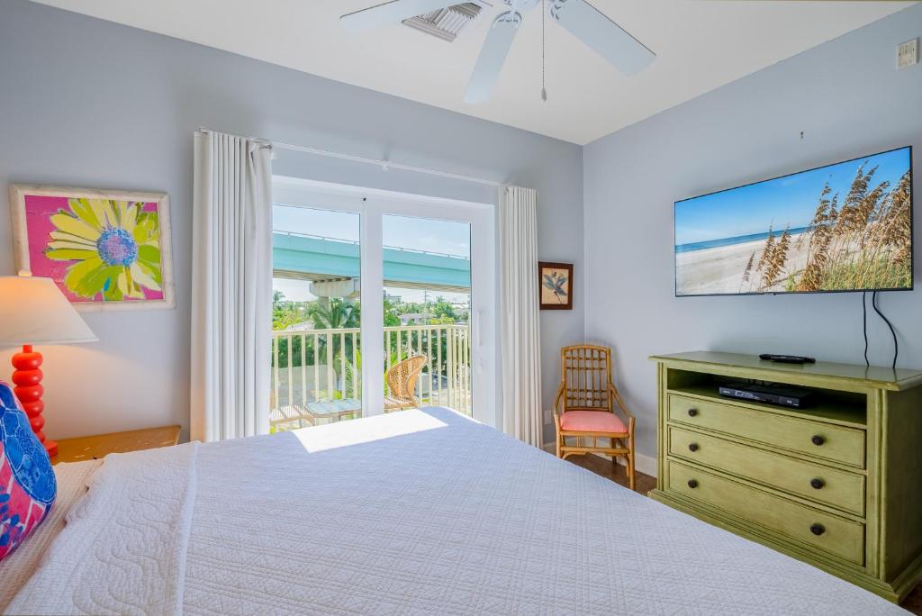 a bedroom with a bed and a television and a balcony at Harbour House at the Inn 315 in Fort Myers Beach
