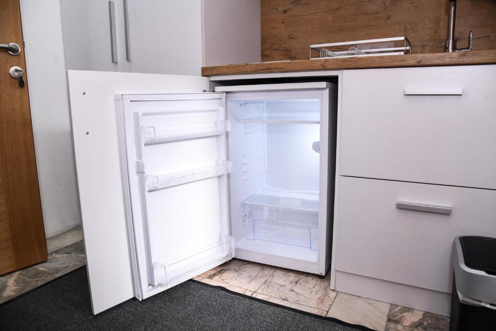 an empty refrigerator with its door open in a kitchen at Demir Apartmani in Novi Pazar