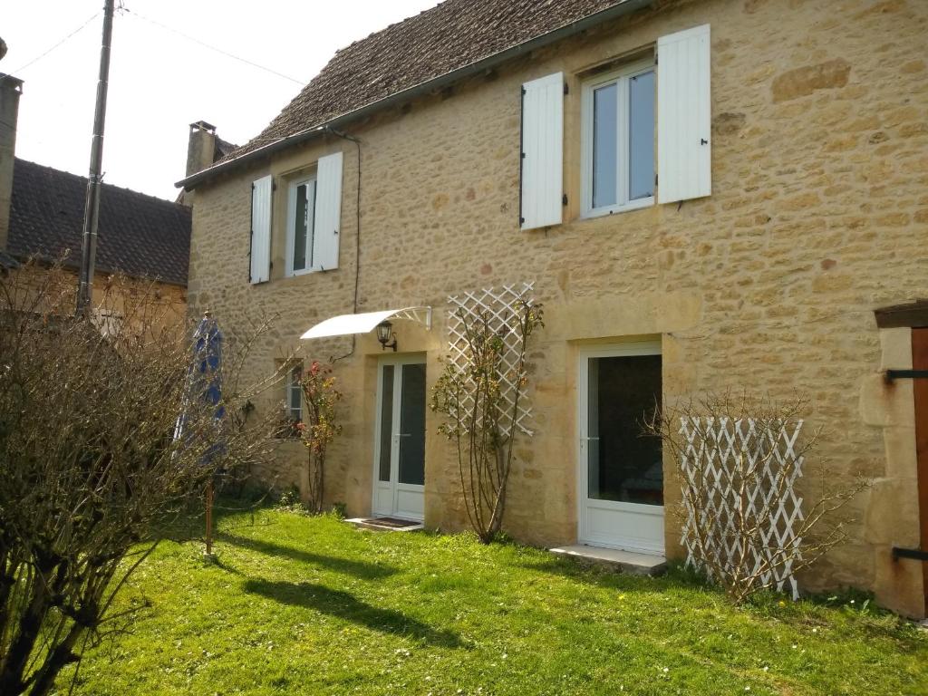 a brick house with white windows and a yard at La Requeyrie in Montignac