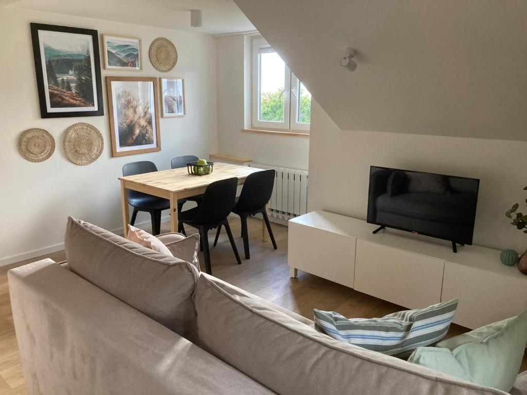 a living room with a couch and a tv and a table at Apartament Tymon in Karpacz